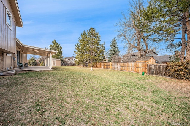 view of yard with a storage shed, a patio, an outbuilding, and a fenced backyard