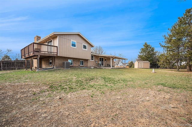 back of property with a storage unit, an outbuilding, fence, a yard, and central AC unit