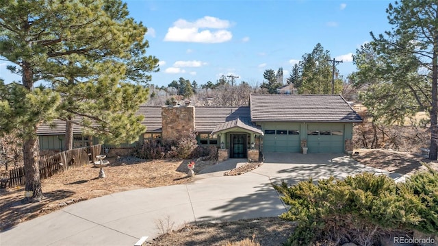 view of front of house with a garage, fence, driveway, a tiled roof, and a chimney