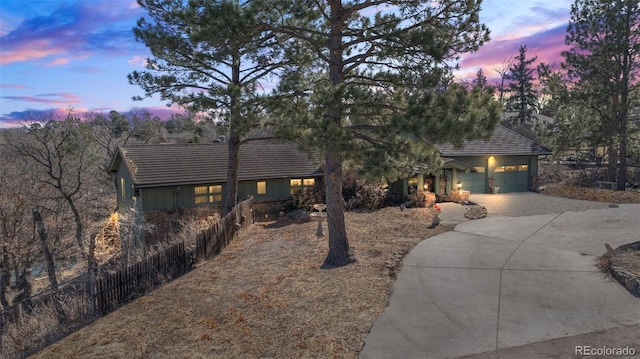 view of front of property with a garage, concrete driveway, fence, and a tiled roof