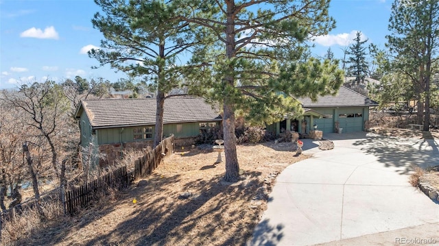 view of front facade featuring a garage, concrete driveway, fence, and a tiled roof