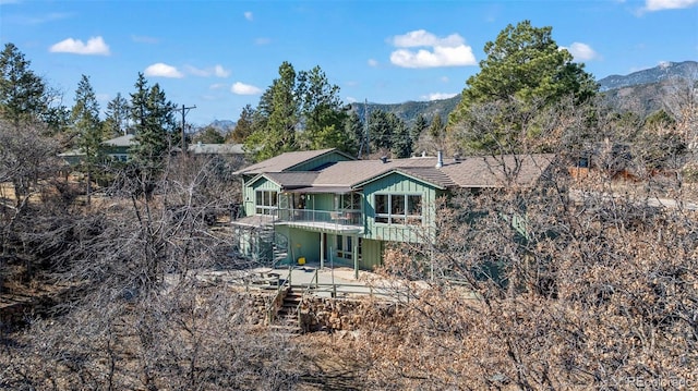 view of front of house with a deck with mountain view, stairs, and board and batten siding