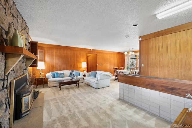 carpeted living area featuring a wood stove, an inviting chandelier, wooden walls, and a textured ceiling