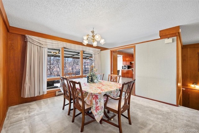 dining space with light colored carpet, wood walls, a textured ceiling, and an inviting chandelier