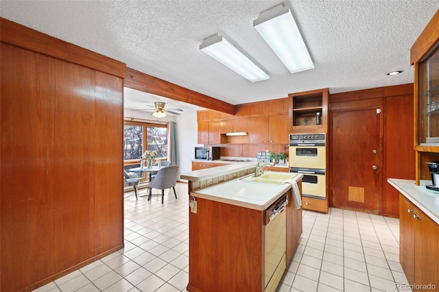 kitchen with light countertops, white appliances, brown cabinetry, and a sink