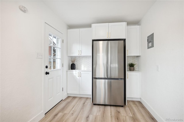 kitchen featuring white cabinets, stainless steel fridge, and light hardwood / wood-style floors