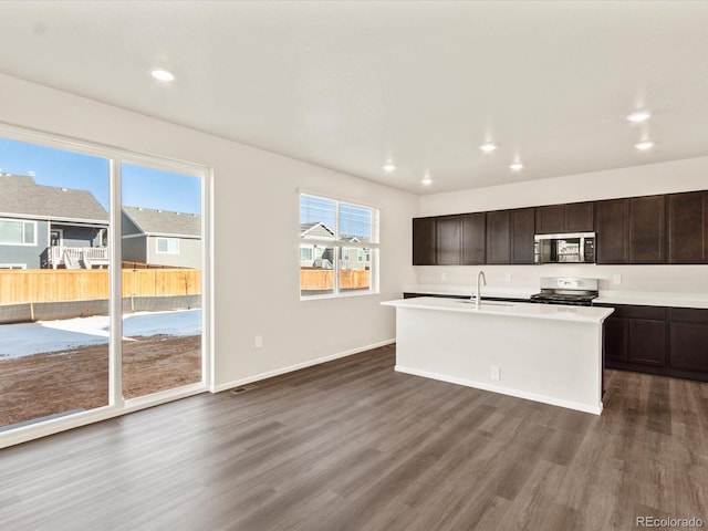 kitchen with dark hardwood / wood-style floors, sink, dark brown cabinetry, a kitchen island with sink, and stainless steel appliances