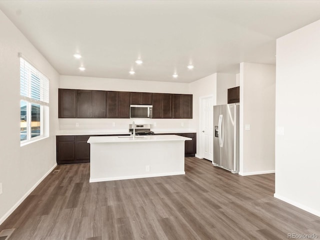 kitchen featuring dark brown cabinets, sink, appliances with stainless steel finishes, an island with sink, and dark hardwood / wood-style flooring