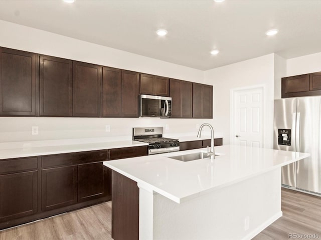 kitchen featuring a center island with sink, sink, light hardwood / wood-style flooring, stainless steel appliances, and dark brown cabinets