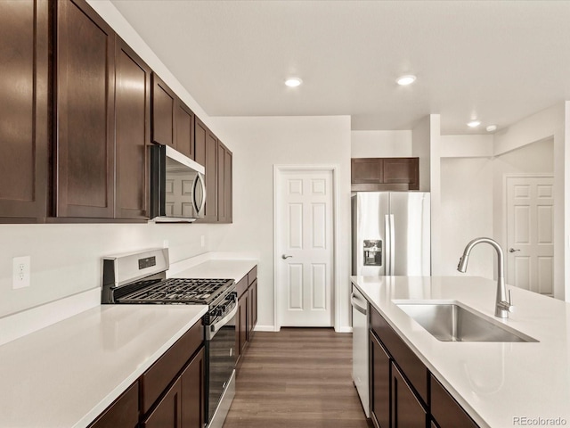 kitchen with appliances with stainless steel finishes, dark brown cabinets, dark hardwood / wood-style flooring, and sink