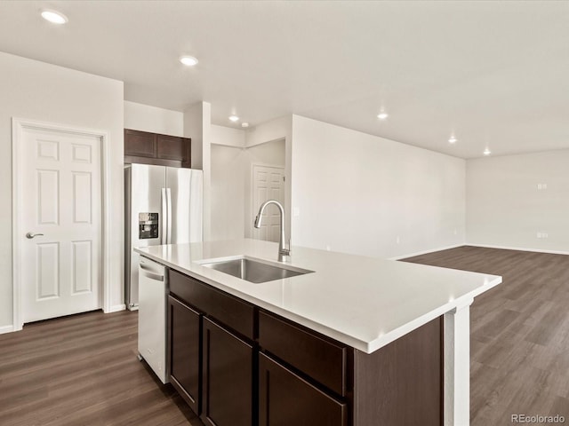 kitchen featuring dark brown cabinetry, dishwasher, dark hardwood / wood-style flooring, sink, and a center island with sink