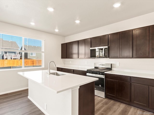 kitchen featuring sink, wood-type flooring, stainless steel appliances, and a kitchen island with sink