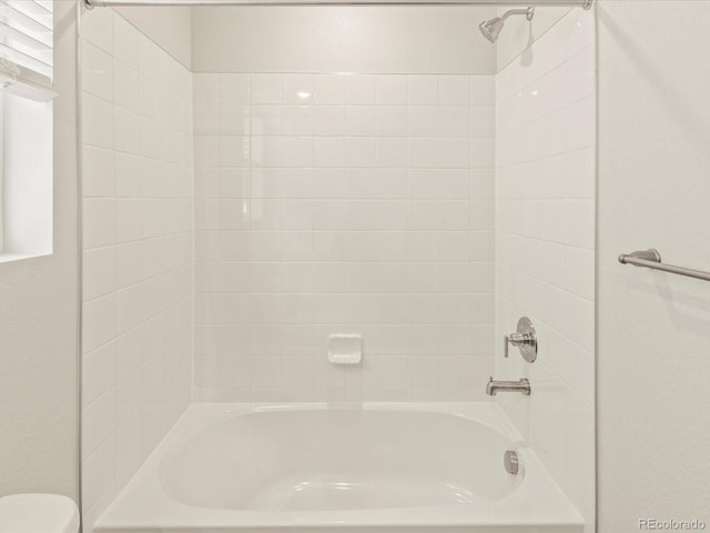 bathroom featuring toilet and tiled shower / bath