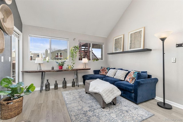 living area featuring baseboards, lofted ceiling, and wood finished floors