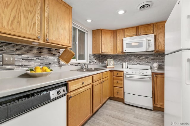 kitchen featuring white appliances, light wood finished floors, a sink, light countertops, and backsplash