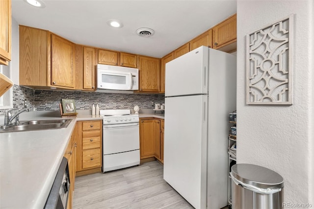 kitchen featuring decorative backsplash, white appliances, visible vents, and a sink