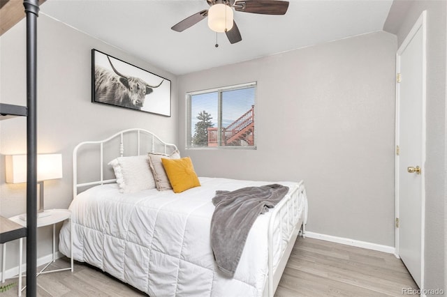 bedroom featuring baseboards, wood finished floors, and a ceiling fan