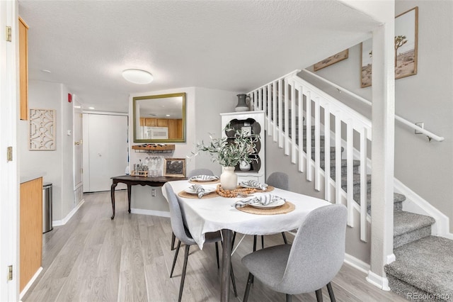 970 S Dawson Way Unit 15, Aurora, CO 80012 - dining area featuring light wood-type flooring, stairway, a textured ceiling, and baseboards