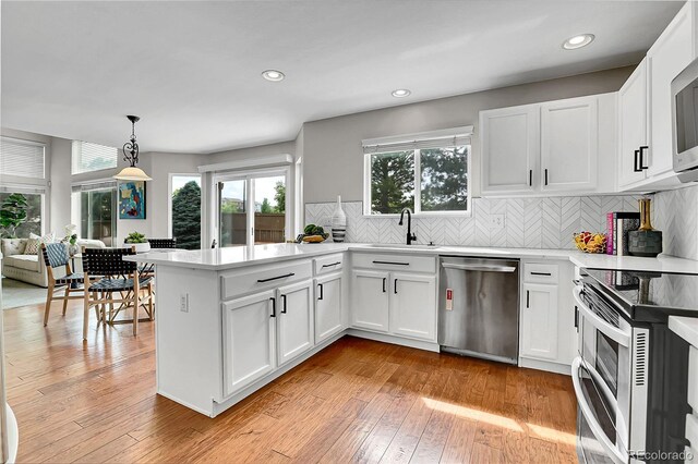 10115 Foxridge Ct, Highlands Ranch, CO 80126 - kitchen with appliances with stainless steel finishes, a peninsula, plenty of natural light, tasteful backsplash, and recessed lighting