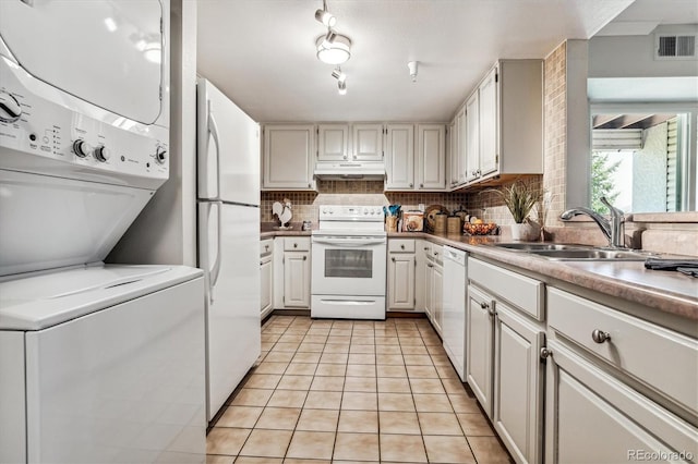 kitchen with white appliances, sink, stacked washer and dryer, light tile patterned floors, and white cabinetry