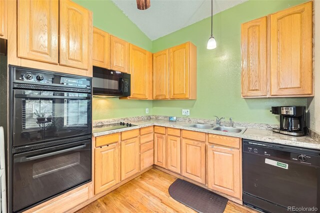 kitchen with lofted ceiling, light brown cabinetry, light wood-type flooring, a sink, and black appliances