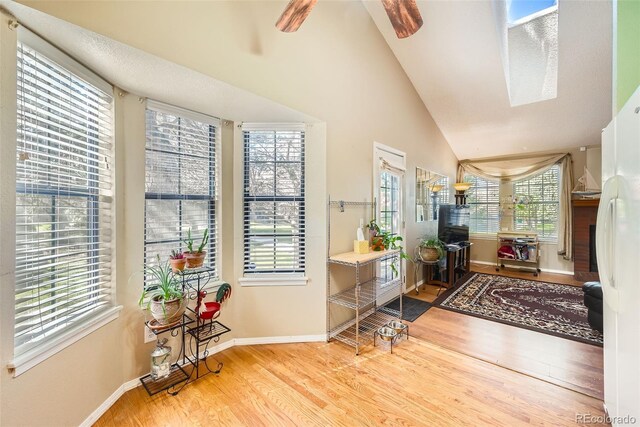 foyer entrance featuring baseboards, ceiling fan, high vaulted ceiling, and wood finished floors