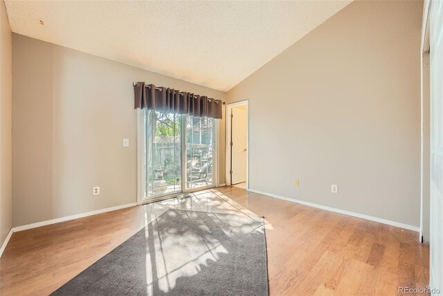 unfurnished room featuring baseboards, lofted ceiling, and wood finished floors
