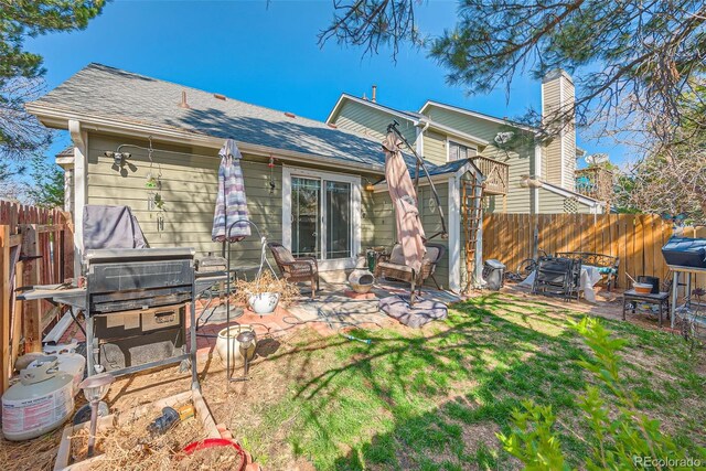 rear view of property featuring a fenced backyard, a patio area, roof with shingles, and a yard