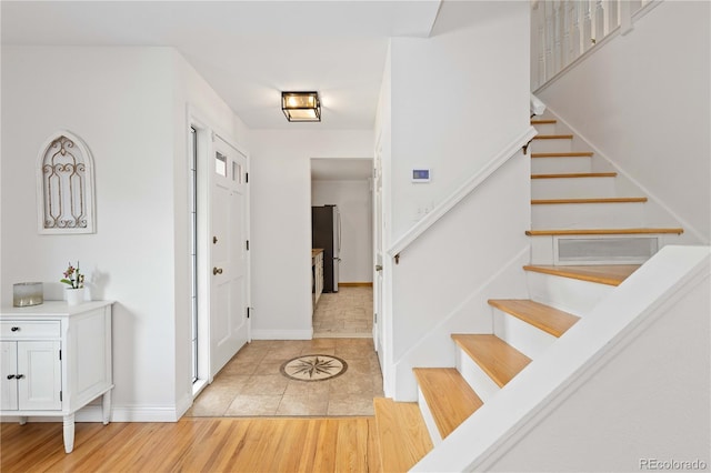 entrance foyer with stairway, baseboards, and light tile patterned floors