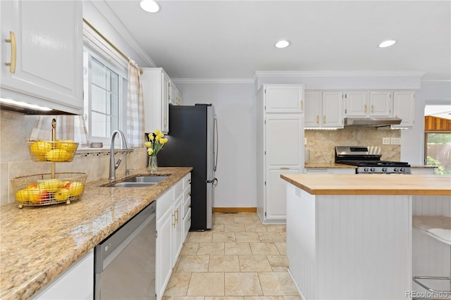 kitchen with stainless steel appliances, under cabinet range hood, a sink, wood counters, and decorative backsplash