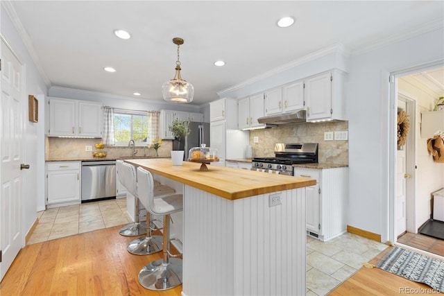 kitchen featuring stainless steel appliances, butcher block countertops, white cabinets, under cabinet range hood, and recessed lighting