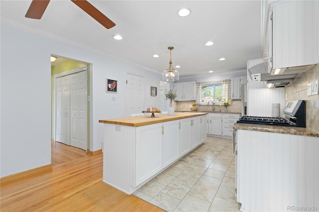 kitchen with wood counters, ornamental molding, white cabinetry, recessed lighting, and backsplash