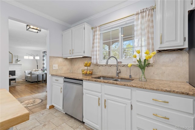 kitchen with stainless steel dishwasher, a sink, light stone countertops, white cabinetry, and ornamental molding