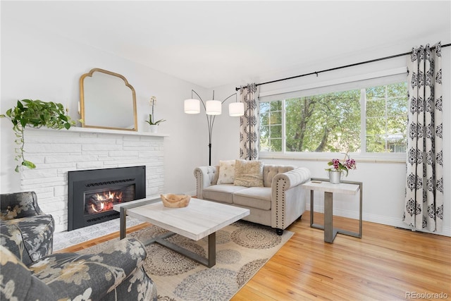 living area with baseboards, a fireplace, and wood finished floors