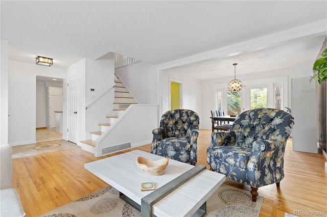 living area featuring stairway, light wood-type flooring, and baseboards