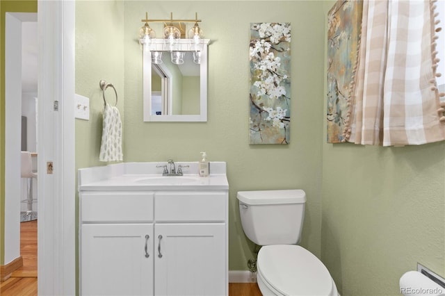 bathroom featuring toilet, vanity, and wood finished floors