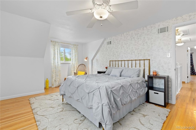 bedroom with light wood-type flooring, baseboards, ceiling fan, and wallpapered walls