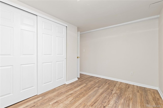 unfurnished bedroom with light wood-style flooring, baseboards, and a closet