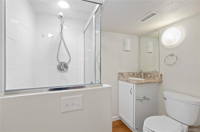 full bath with toilet, tiled shower, and vanity