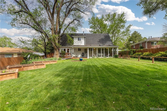 back of property with a vegetable garden and a sunroom