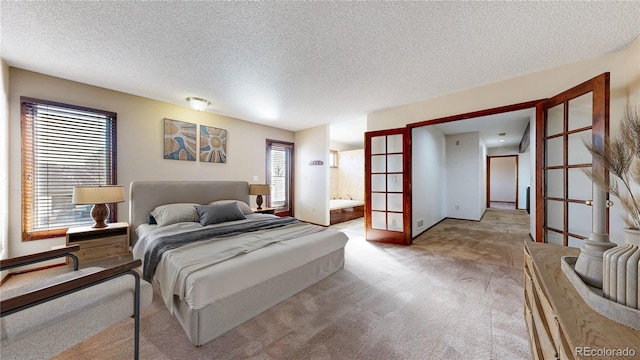 bedroom with light carpet, french doors, a textured ceiling, and ensuite bath