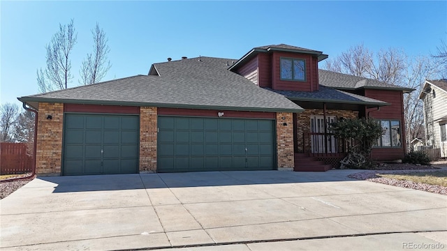 view of front facade featuring a garage, brick siding, driveway, and a shingled roof