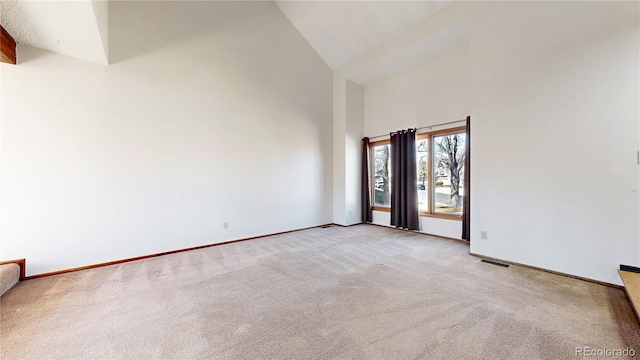 spare room with light carpet, high vaulted ceiling, baseboards, and visible vents