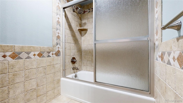 full bathroom with shower / bath combination with glass door and tile walls