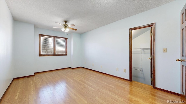 spare room featuring light wood-style floors, a textured ceiling, and baseboards