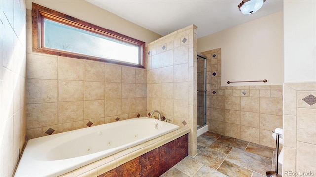 bathroom with a jetted tub, a shower stall, tile walls, and stone finish flooring