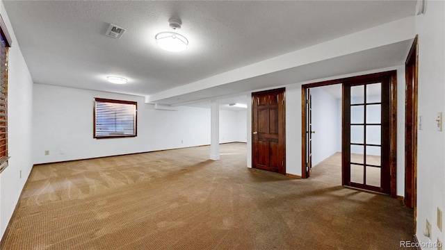 empty room featuring a textured ceiling, carpet, and visible vents