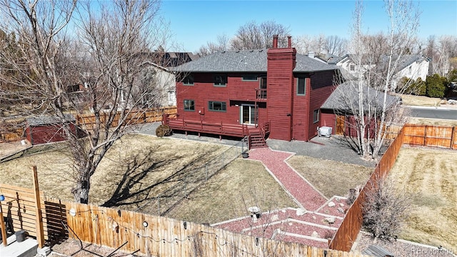 back of house featuring a deck, a chimney, and a fenced backyard