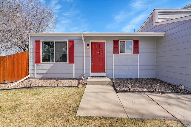 doorway to property featuring a yard and fence