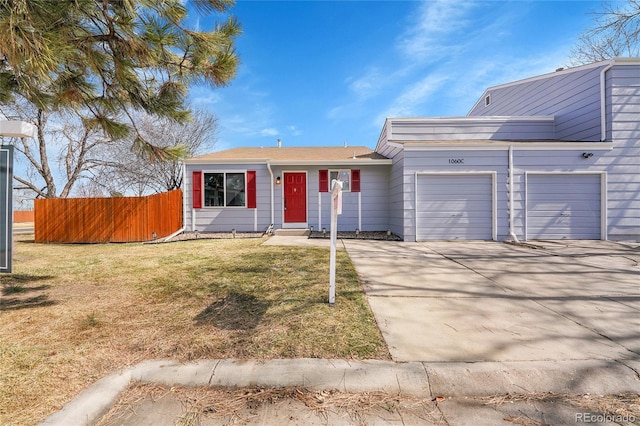 view of front of property with a garage, concrete driveway, fence, and a front lawn